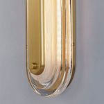 Close-up angled view of lit wall sconce with aged brass bar and clear glass frame