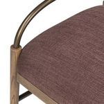 Close-up focus on top of cushion with bronze arm curving above textured fabric