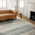 Jocelyn Sky Multi rug styled in living room with caramel leather sofa, wood side table, and white brick fireplace