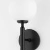Wall sconce shown mounted on white wall at slight angle showing round backplate and globe