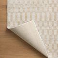 Kamala rug sample corner flipped up showing woven fabric backing on wood floor