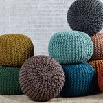 Multiple Spectrum Poufs in various colors stacked and arranged, showcasing knitted texture and round shapes