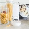 Bianca canister open with pasta spilling slightly, lid resting on kitchen counter