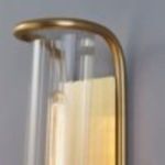 Close-up of top curved polished nickel arm of sconce with warm light glow