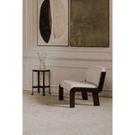 Simple interior vignette with chair on carpeted floor in front of paneled wall and large art