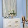Chest styled in a light blue room with artwork and decorative objects on top