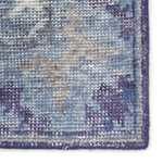 Close-up of rug corner showing detailed hand-knotting and woven texture with blue and gray tones.