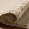 Corner of the rug lifted to show thickness and wool texture on dark wood floor