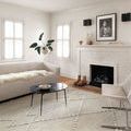 Rug in a modern living room setting with fireplace, light sofa, and black round coffee table