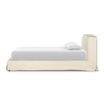 Side view of queen bed with cream linen slipcover and white bedding