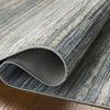 Side view of rug partially rolled up showing backing material and flexible polyester weave