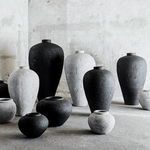 Black and white textured vases grouped together on concrete floor in natural light with rustic background