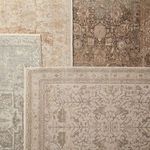 Overhead view of rug partially covered by layered beige and cream woven textiles with geometric pattern.