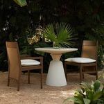 Pair of outdoor arm chairs with oak finish and white cushions, shown with round white outdoor table in garden