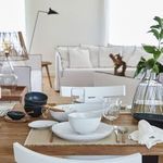 Side view of Livia bowl on plates with additional black bowls and wooden utensils on dining table