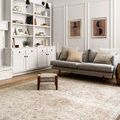 Loren Sand Taupe rug in bright room featuring gray sofa, woven stool, and white shelves