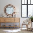 End table styled in a bright room next to woven chair and natural wood sideboard