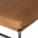 Close-up of leather seat cushion corner with visible stitched seam and metal frame beneath