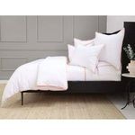 Side view of duvet set showing soft pink piping on duvet and smartly arranged pillows on dark bed frame