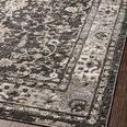 Estelle rug angled close-up on wood floor emphasizing muted border and floral details