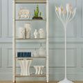 Shelving unit holding white floral porcelain vases alongside other decorative objects and a sculptural white floor lamp