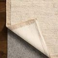 Rug corner peeled back to reveal backing and layering details on smooth brown floor