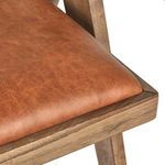 Detailed close-up of Dolton Arm Chair’s smooth leather seat cushion and wooden frame corner