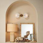 Styled room setting with two alabaster sconces above mirror and natural wood decor