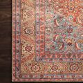 Detailed close-up of Loren rug's floral pattern near a dark wood floor edge