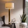 Styled table with decorative glass orbs, beige armchair, brass floor lamp, and large window