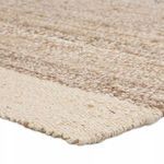 Close-up of rug corner highlighting flat woven texture and tan stripes with white border
