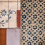 Fabric swatches with blue floral pattern on tan paper and rust, lavender, and brown textile pieces