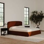 Joan King Storage Bed positioned between two black nightstands with large plants and windows