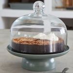 Artichoke footed plate shown with a clear glass dome and a chocolate cake topped with whipped cream inside