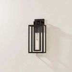 Amire sconce angled on wall showing slender off-white candle and glowing filament bulb inside glass panels