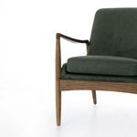 Partial angle focusing on cushion edge and front leg of chair's handcrafted oak base