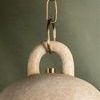 Detailed view of the curved handle and brass chain attachment on the pendant
