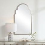 Olivia Mirror hanging on wall above console table with lamp and glass vase with flowers