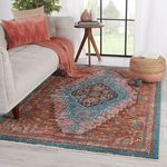 Rug styled in living room setting under coffee table and sofa, complemented by coordinated rust-colored pillows and throw