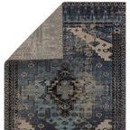 Back corner of the rug flipped over revealing the reverse side with a muted gray pattern.
