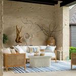 Playa sofa styled in outdoor patio setting with decorative pillows, ceramic table, and textured blue-striped rug