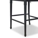 Close-up of the stool’s slightly rounded black-finished legs and footrest support bars