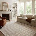Polly rug styled in bright living room setting with beige sofa, leather chair, and marble fireplace