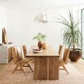 Cecelia Rust Natural Rug styled under a modern wood dining table with chairs and green plants in bright room