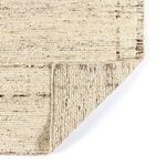 Corner of rug folded to reveal hand-knotted wool texture on front and back sides