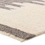 Close-up showing tufted wool texture and gray fringe detail along edge of the rug