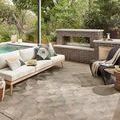 Rug styled outdoors under pergola, paired with modern sofa, pillows, fireplace, and wicker chairs