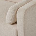 Close-up view of corner seat section showing back and arm cushions in cream fabric