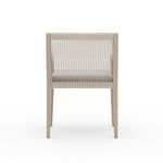 Sherwood Brown armchair positioned next to wooden outdoor dining table with natural stone tile flooring