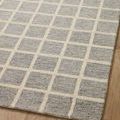 Angled close-up of Polly Slate Ivory Rug on wood flooring focusing on edges and grid detail